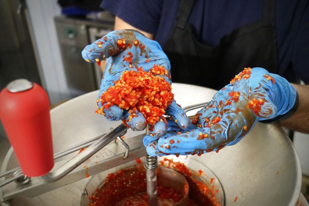 Chili sauce being crushed and mixed by hand